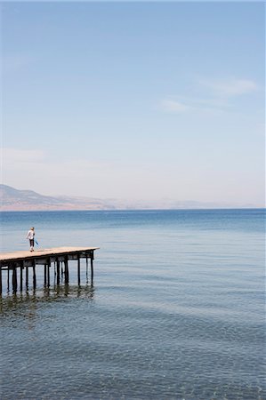 people walking in the distance - Boy With Dip Net On Pier Stock Photo - Premium Royalty-Free, Code: 649-03008549