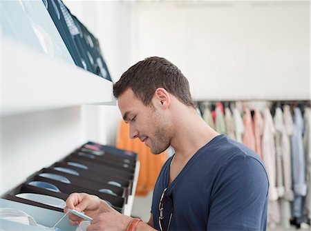 racks of clothing - man shopping looking at label Stock Photo - Premium Royalty-Free, Code: 649-03008751