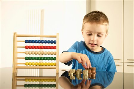 stacks of coins - boy with money and abacus Stock Photo - Premium Royalty-Free, Code: 649-03009851