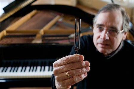 Piano tuner holding tuning fork Stock Photo - Premium Royalty-Free, Code: 649-03010111