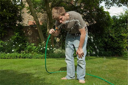 Boy drinking water from hosepipe Stock Photo - Premium Royalty-Free, Code: 649-03153826