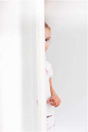 simsearch:632-03193343,k - young girl looking around corner Foto de stock - Royalty Free Premium, Número: 649-03295946