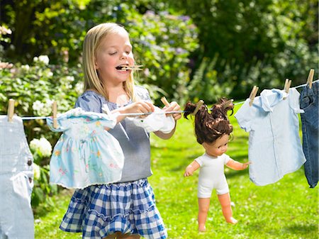 Girl spreading out her doll clothes Stock Photo - Premium Royalty-Free, Code: 649-03296425