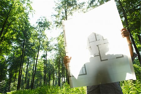 Man in the woods, looking at blueprint Stock Photo - Premium Royalty-Free, Code: 649-03296429