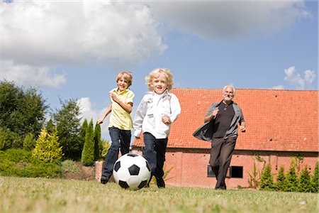 senior man looking up smiling - grandfather and kids playing football Stock Photo - Premium Royalty-Free, Code: 649-03297271
