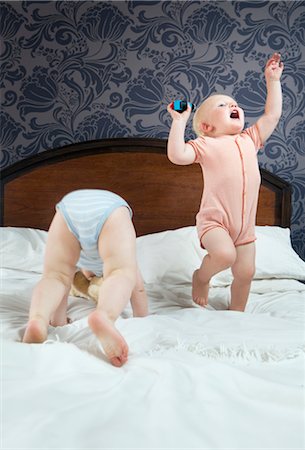 Two baby boys play on a bed Stock Photo - Premium Royalty-Free, Code: 649-03292634