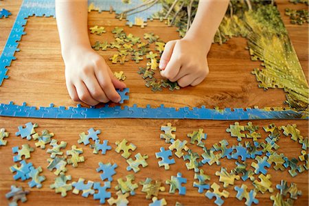 puzzles - Some hands working on a puzzle Foto de stock - Sin royalties Premium, Código: 649-03292945