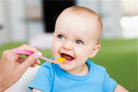 püree - baby sitting in chair being fed Foto de stock - Sin royalties Premium, Código: 649-03362701