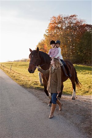 family road - Woman walking a horse with two girls Stock Photo - Premium Royalty-Free, Code: 649-03418544