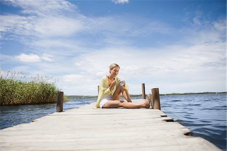 relaxing on dock - Woman eating a yogurt Stock Photo - Premium Royalty-Free, Code: 649-03447190