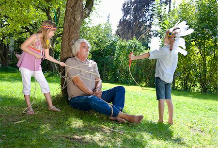 sunlight fun outdoor game - Grandchildren got their grandfather tied Stock Photo - Premium Royalty-Free, Code: 649-03448398