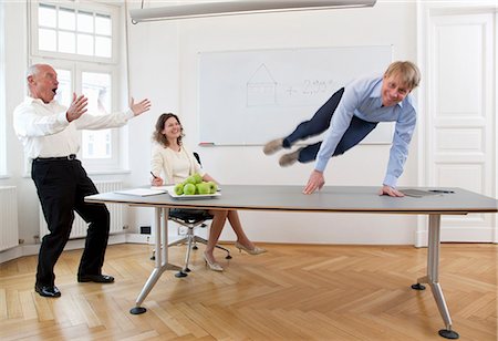 soupçon (suspicion) - Homme d'affaires sautant par-dessus la table Photographie de stock - Premium Libres de Droits, Code: 649-03465854