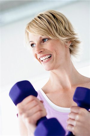 Woman with weights smiling Stock Photo - Premium Royalty-Free, Code: 649-03510822