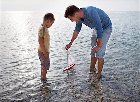 Father and son with toy boat at beach Stock Photo - Premium Royalty-Free, Code: 649-03511050