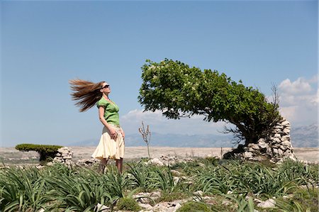 Woman with windblown hair and tree Stock Photo - Premium Royalty-Free, Code: 649-03511077