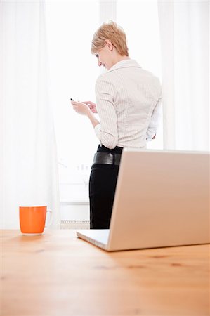 person desk rearview - Woman using cellphone, smiling Stock Photo - Premium Royalty-Free, Code: 649-03566089