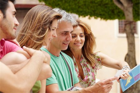 Two couples looking at postcard Stock Photo - Premium Royalty-Free, Code: 649-03566363