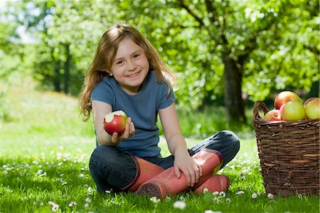 Girl in meadow, eating apple Stock Photo - Premium Royalty-Free, Code: 649-03566561