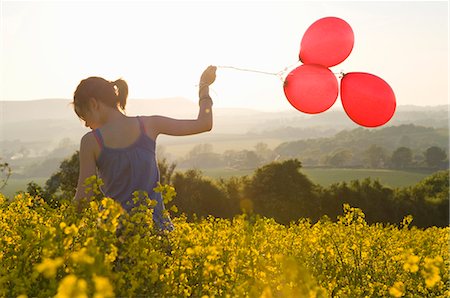 Girl walks thru field with balloons Stock Photo - Premium Royalty-Free, Code: 649-03566980