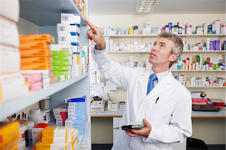 prescription doctor - Pharmacist looking at shelf of pills Stock Photo - Premium Royalty-Free, Code: 649-03621586