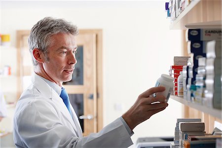 pharmacy shelf - Pharmacien en regardant une bouteille de pilules Photographie de stock - Premium Libres de Droits, Code: 649-03621581