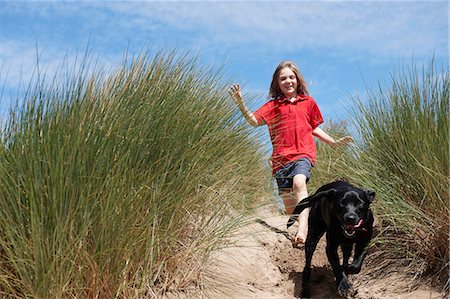 seagrass - Young Girl Chasing dog in sand dunes Stock Photo - Premium Royalty-Free, Code: 649-03768900