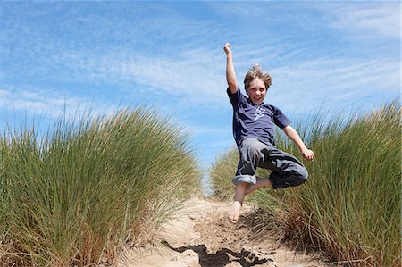 simsearch:649-06716899,k - Young boy jumping in sand dunes Foto de stock - Royalty Free Premium, Número: 649-03768901