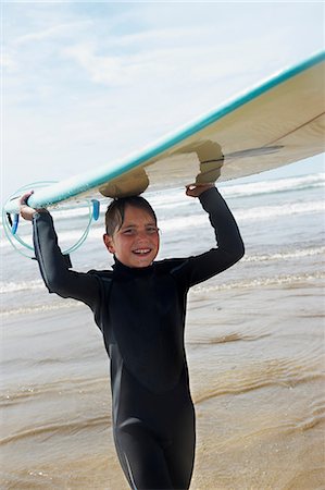 Young boy with surf board on his head Stock Photo - Premium Royalty-Free, Code: 649-03768927
