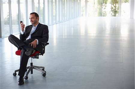 Businessman on a chair, in empty office Stock Photo - Premium Royalty-Free, Code: 649-03769499