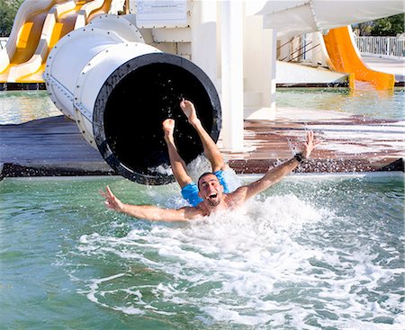 splashing in pool - Young man falls into pool from slide Stock Photo - Premium Royalty-Free, Code: 649-03774850