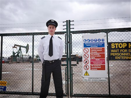 Security guard at gate of oil well Stock Photo - Premium Royalty-Free, Code: 649-03770354