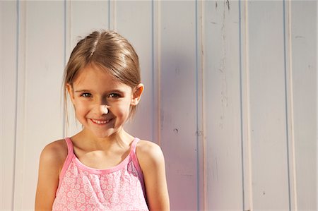 Little girl in front of a wooden wall Stock Photo - Premium Royalty-Free, Code: 649-03770678