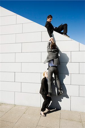 suit man standing backside - 2 people helping man over wall Foto de stock - Sin royalties Premium, Código: 649-03772109