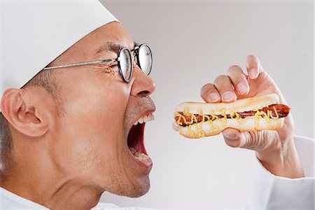 ethnic man eating hot dog - Chef about to eat a hotdog Stock Photo - Premium Royalty-Free, Code: 649-03772278