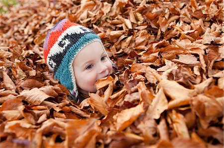 side profile of a kid face - Girl buried in autumn leaves Stock Photo - Premium Royalty-Free, Code: 649-03773973