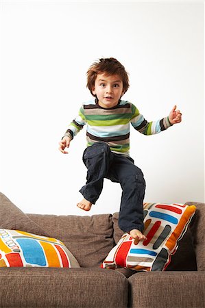 Boy jumping on sofa Foto de stock - Sin royalties Premium, Código: 649-03796074