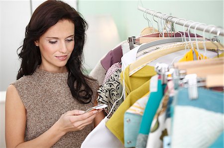 racks of clothing - woman checking price tag Stock Photo - Premium Royalty-Free, Code: 649-03797060