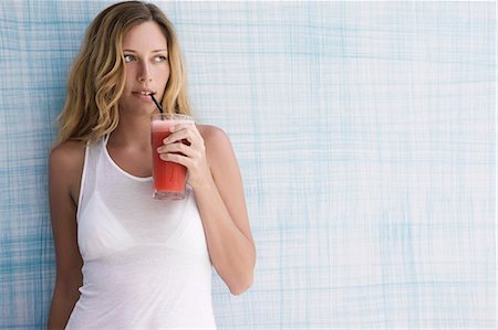 person drinking smoothie - Girl up against blue wall with red smoothie, looking to the side Stock Photo - Premium Royalty-Free, Code: 649-03797430