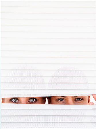 Two women look through blinds Stock Photo - Premium Royalty-Free, Code: 649-03797592