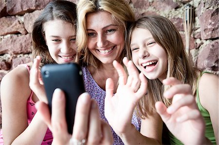 excited person holding a phone - Mother and daughters video call on phone Stock Photo - Premium Royalty-Free, Code: 649-03817287