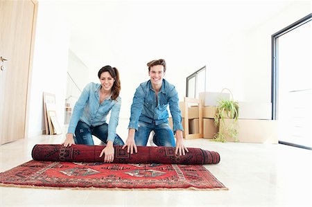 Couple unrolling carpet in new home Stock Photo - Premium Royalty-Free, Code: 649-03857364