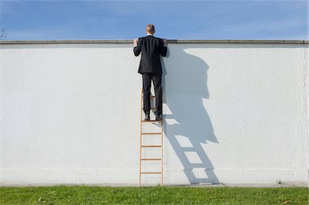 Businessman on ladder looking over wall Foto de stock - Sin royalties Premium, Código: 649-03857388