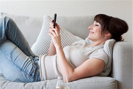 Woman using cell phone on couch Foto de stock - Sin royalties Premium, Código: 649-03857411