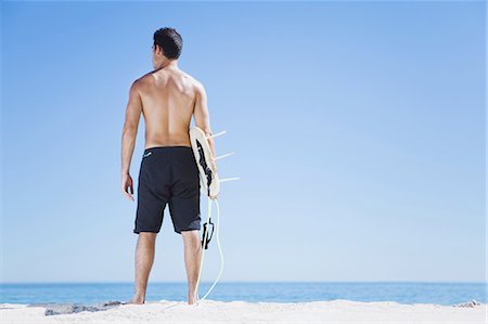 simsearch:649-03465846,k - Man carrying surfboard on beach Stock Photo - Premium Royalty-Free, Code: 649-03857457