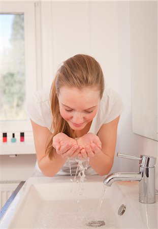 person cupping water - Teenage girl washing face in bathroom Stock Photo - Premium Royalty-Free, Code: 649-03857859