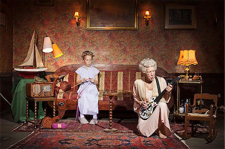 family active playing - Older woman playing guitar as girl knits Stock Photo - Premium Royalty-Free, Code: 649-03858053