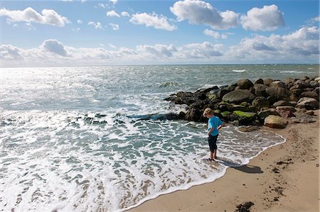 simsearch:649-05658170,k - Boy standing in surf at the beach Foto de stock - Royalty Free Premium, Número: 649-03858355