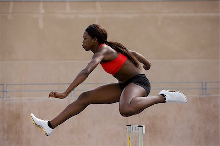 Runner jumping over hurdles on track Stock Photo - Premium Royalty-Free, Code: 649-03884073