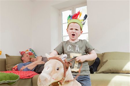family lifestyle funny - Boy in war bonnet playing with toys Stock Photo - Premium Royalty-Free, Code: 649-03884187