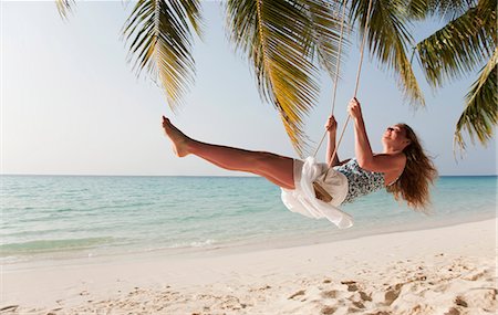 simsearch:841-06342803,k - Smiling woman swinging on tropical beach Fotografie stock - Premium Royalty-Free, Codice: 649-03881283